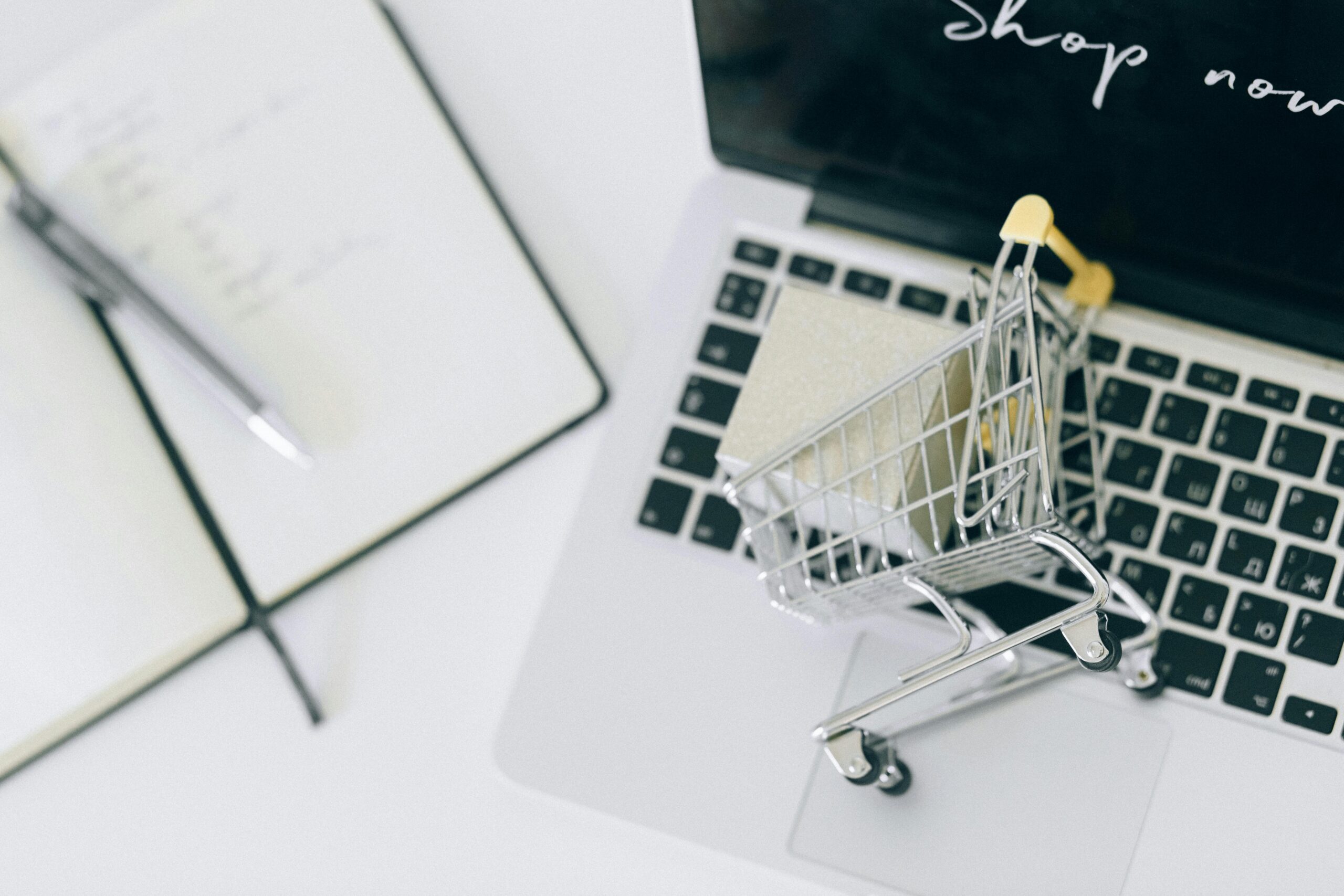 Miniature shopping cart on laptop keyboard representing eBay account setup for Korean buyers