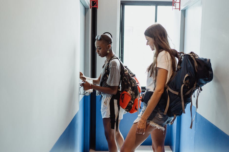 Two travelers with backpacks at a Korea hostel corridor