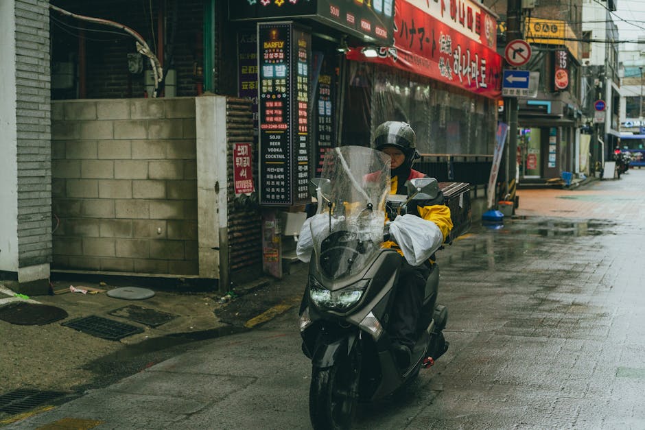 Delivery scooter navigating Seoul alley on a rainy day